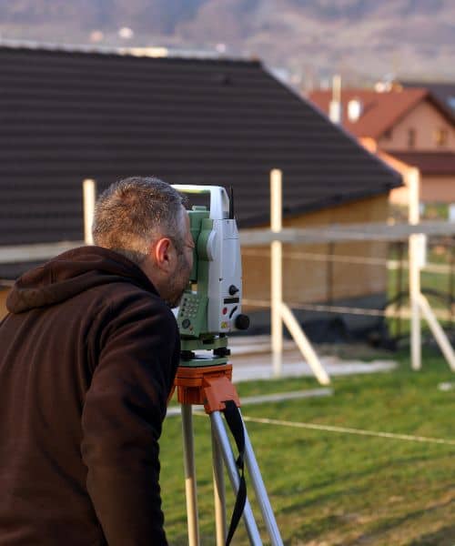 Land surveyor using total station to measure property lines during a loan closing survey