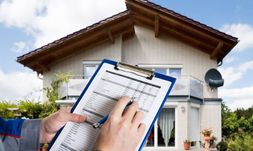 Home inspector reviewing a loan closing survey in front of a house