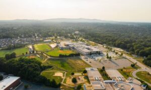 Aerial view of a school campus with parking areas, athletic fields, and surrounding streets, showing the site features a due diligence survey can document