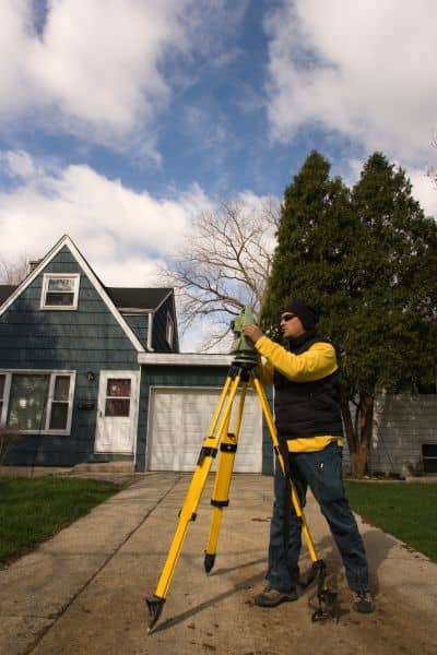 Licensed land surveyor using equipment to conduct a boundary line survey in a Chicago neighborhood
