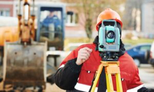 Land surveyor using total station for a topographic survey in Chicago construction site to support flood risk assessment