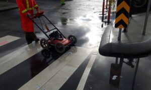 A construction survey technician using ground penetrating radar to map underground utility lines before excavation