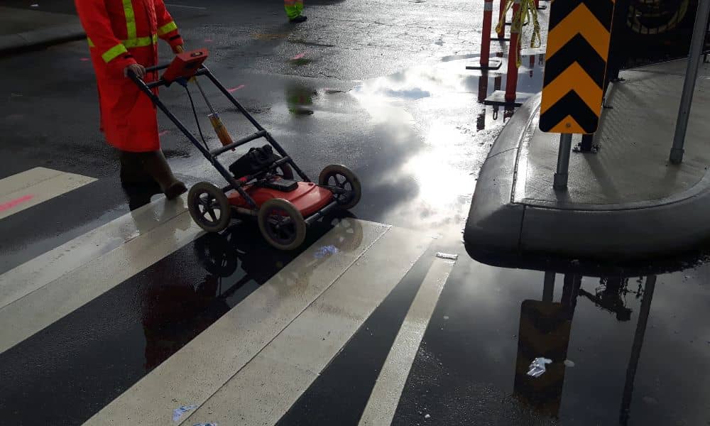 A construction survey technician using ground penetrating radar to map underground utility lines before excavation