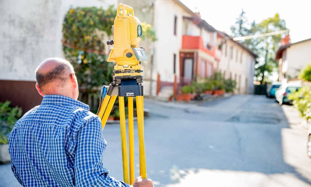Land surveyor performing a boundary line survey between closely spaced residential properties