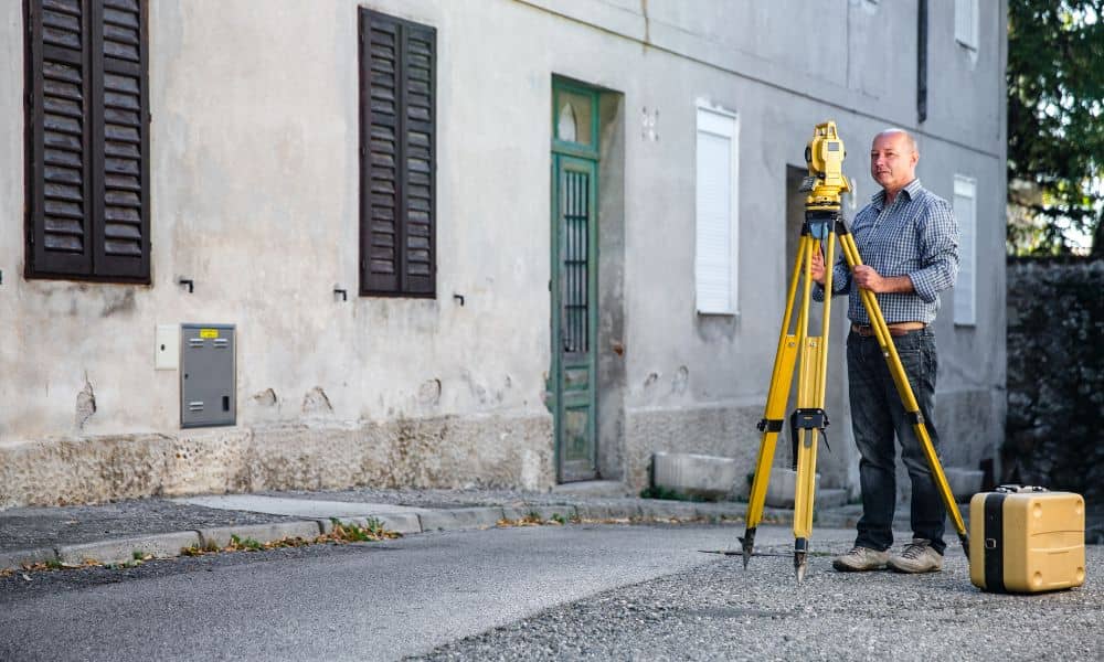 Surveyor performing a topographic survey on a city street development site