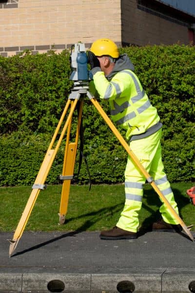 Licensed land surveyor measuring property boundaries for a plat of survey