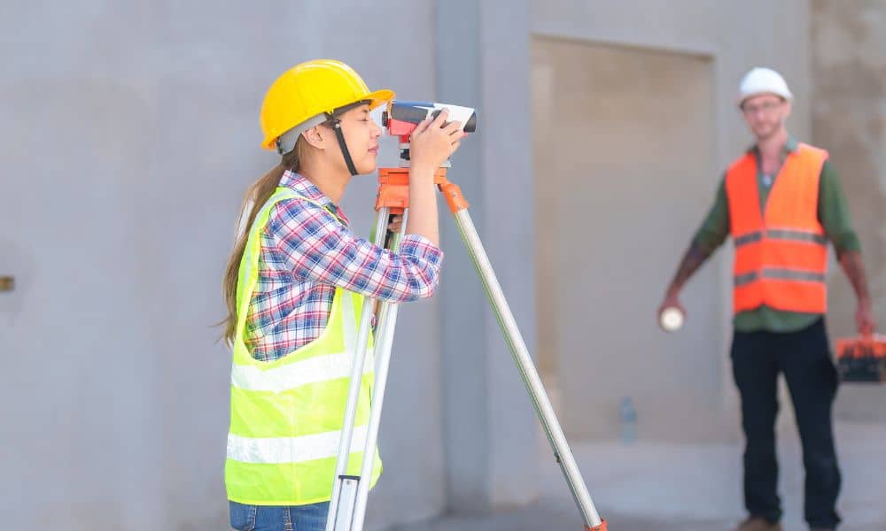 Surveyor performing a construction survey using a total station on a building site