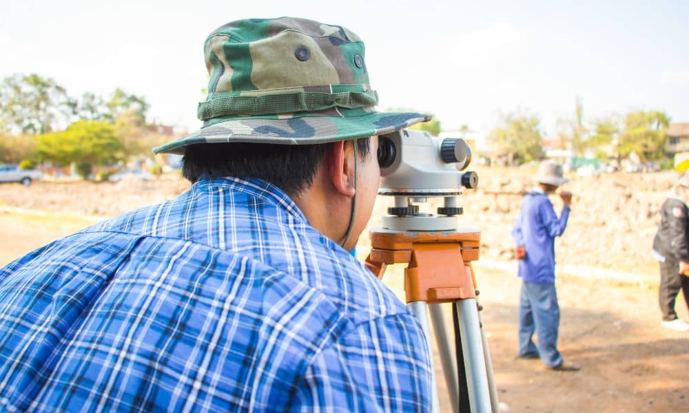 Surveying companies using equipment to measure land and locate utilities on a construction site